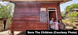 Enos Marajani bersama anggota keluarganya berfoto di depan huntara individual yang disebut sebagai rumah tumbuh di desa Sungku, Kecamatan Kulawi, Kabupaten Sigi, Sulawesi Tengah. (Foto : Dewi Sri Sumanah/Save the Children Indonesia)