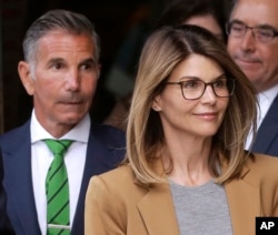Actress Lori Loughlin, front, and husband, clothing designer Mossimo Giannulli, left, depart federal court in Boston after facing charges in a nationwide college admissions bribery scandal, Apr. 3, 2019.