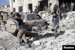 FILE - Residents carry an injured woman on a stretcher in a site hit by airstrikes in the rebel-controlled area of Maarat al-Numan town in Idlib province, Syria, Jan. 9, 2016.
