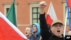 A supporter of a right wing organization gestures, as others shout slogans during an anti-migrant rally in Warsaw, Poland, Sept. 26, 2015.