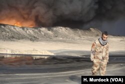 Locals secure the area around the fire in conjunction with the Iraq Army, but can do nothing to put it out in Qayyarah, Iraq, Nov. 5, 2016.