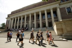 Orang-orang berjalan melewati pintu masuk Perpustakaan Widener, di belakang, di kampus Universitas Harvard, di Cambridge, AS (Foto: AP/Steven Senne)