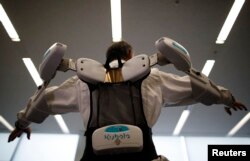 FILE - An employee of ActiveLink Co. established under the intrapreneurship of Panasonic Corp, demonstrates a robotic exoskeleton developed to help farmers and construction workers.