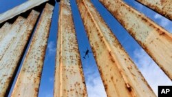 FILE - A helicopter monitors the U.S. border fence from above, seen from Tijuana, Mexico, Dec. 23, 2018.