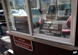 Vehicles pass by freely in the background as a fee booth sits unmanned at the east entrance to Rocky Mountain National Park, in Estes Park, Colo., Jan. 20, 2018. National parks are to remain as "accessible as possible" during a government shutdown that began Jan. 20.