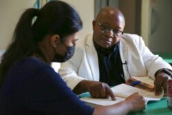 Parishioner and translator Berenice Velazquez, left, helps the Rev. Athanasius Abanulo with his Spanish before the afternoon Mass at Immaculate Conception Catholic Church in Wedowee, Ala., Dec. 12, 2021.