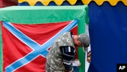 A Pro-Russia rebel arranges a flag of self-proclaimed Novorossiya (New Russia) as some separatists call the territories they hold in eastern Ukraine, in the city of Donetsk, Sept. 16, 2014.