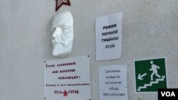 A face mask of Russian communist revolutionary Vladimir Lenin is seen mounted on a wall at the Vershina-Navigator Foundation's rehabilitation center. The sign beneath reads “I’m also addicted. Revolution is my narcotic!”