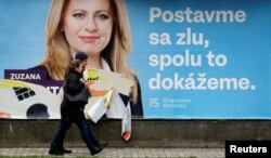 People walk past an election poster of Slovakian presidential candidate Zuzana Caputova in Bratislava, Slovakia, March 15, 2019. The poster reads: "President for fair Slovakia. Stand up against evil, together we can do it."
