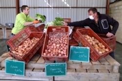 Vegetable grower Didier Lenoble, wearing a protective face mask, poses among boxes with vegetable put on sell during the outbreak of Coronavirus disease (COVID-19) in Perigny-sur-Yerres, France, March 31, 2020. (REUTERS/Charles Platiau)