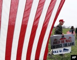 A supporter of President Donald Trump walks by during a rally for the president's visit, March 13, 2018, in San Diego. Trump on Tuesday inspected prototypes on display in California for his "big, beautiful border wall."