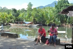 A woman and her neighbor chat while she sorts fish in this small fishing town along Ulugan Bay, which fronts the South China Sea, in Bahile, Palawan province, Philippines. (Photo: Simone Orendain for VOA)