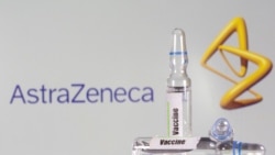 A test tube labeled with the vaccine is seen in front of AstraZeneca logo