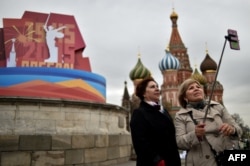 Women pose for a selfie in front of the historical Place of Execution decorated with a banner for the upcoming Victory Day celebrations on the Red Square in central Moscow, April 30, 2015.
