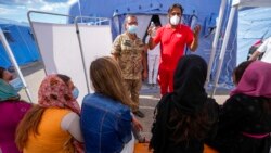 FILE - Afghan refugees listen to instructions before getting COVID-19 vaccine shots in an Italian Red Cross refugee camp, in Avezzano, Italy, Aug. 31, 2021.