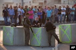 Israeli border police check Palestinian's IDs at a checkpoint as they exit the Arab neighborhood of Issawiyeh in Jerusalem, Oct. 18, 2015.