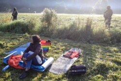 Prajurit Polandia dan petugas patroli perbatasan menjaga sekelompok migran yang terdampar di perbatasan antara Belarus dan Polandia di dekat desa Usnarz Gorny, Polandia, 22 Agustus 2021. (Foto: Grzegorz Dabrowski/Agencja Gazeta via REUTERS)