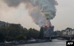 Smokes ascends as flames rise during a fire at the landmark Notre-Dame Cathedral in central Paris on April 15, 2019 afternoon, potentially involving renovation works being carried out at the site, the fire service said.