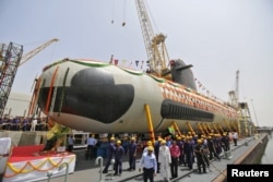 Employees stand near the Indian Navy's first Scorpene submarine before being undocked at a naval vessel ship building yard, in Mumbai.