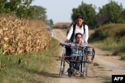 FILE - Nujeen Mustafa, refugee from Syria in a wheelchair moves toward the Croatian village of Tovarnik, close to the official Serbia-Croatia border, Sept. 16, 2015.