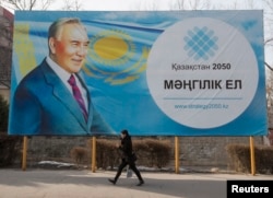 A woman walks past a poster depicting Kazakhstan's President Nursultan Nazarbayev in Almaty, Feb. 16, 2015.
