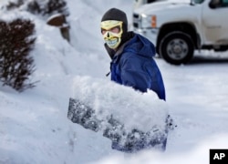 In Maine with the temperature at 3 degrees Fahrenheit, this man shovels snow wearing a face mask to guard against frostbite, January, 2014.
