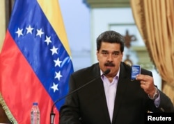 Venezuela's President Nicolas Maduro holds a copy of the Venezuelan constitution while he speaks during a meeting with members of the Venezuelan diplomatic corp after their arrival from the United States, at the Miraflores Palace in Caracas, Venezuela, Jan. 28, 2019.