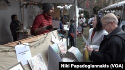Artist Carlos Carmonamedina talks to customers while selling his postcards in Washington, D.C.