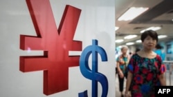 Simbol mata uang yuan (kiri) dan dolar AS di sebuah tempat pertukaran mata uang di Hong Kong.