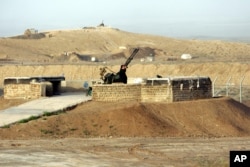 FILE - A security man stands next to an anti-aircraft gun as he scans around Iran's nuclear enrichment facility in Natanz, 300 kms 186 (miles) south of capital Tehran, Iran.