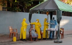 Pejabat kesehatan Sri Lanka melakukan tes usap saat mereka melakukan skrining acak untuk COVID-19 di area terkunci di Kolombo, Sri Lanka, Senin, 20 April 2020. (Foto: AP)