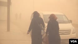 Families hurry indoors as the sandstorm begins, saying although the current local leadership provides security, they are still without electricity and hospitals, in al-Shadady, Syria, Oct. 28, 2017. (H. Murdock/VOA)