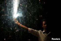 A man holds a firecracker while celebrating the Hindu festival of Diwali, the annual festival of lights in Mumbai, India, Oct. 19, 2017.