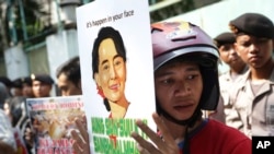 Seorang aktivis memegang poster potret pemimpin oposisi Myanmar Aung San Suu Kyi dalam sebuah protes menuntut diakhirinya kekerasan terhadap etnis Rohingya di negara bagian Rakhine, di luar Kedutaan Besar Myanmar di Jakarta, Indonesia, 29 Mei 2015.