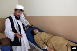 FILE - An Afghan patient is seen on the bed as a father weeps in the Mental Health and Drug Addicts' Hospital in Kabul, Afghanistan.