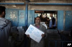 Palestinians receive food aid at a U.N. Relief and Works Agency warehouse in the Shati refugee camp, Gaza City, Jan. 14, 2018.