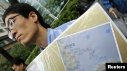 Seorang aktivis Korea Selatan menunjukkan gambar peta pulau Dokdo yang dihapus namanya dalam fitur aplikasi peta baru keluaran Apple dan Google (foto: dok).