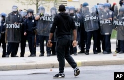 FILE - A demonstrator clutching a brick faces a line of police officers amid tension after Freddie Gray's funeral in Baltimore, April 27, 2015.