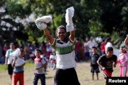 A man holds up supplies after an Indonesian Red Cross helicopter dropped aid to the earthquake affected area in Sirenja, Donggala Regency, Central Sulawesi, Indonesia, Oct. 5, 2018.