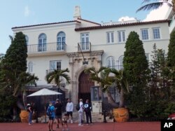 Tourists pose for photographs and read a restaurant menu in front of The Villa Casa Casuarina, a boutique hotel in Miami Beach, Fla.