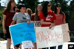 Sonja Breda, 23, right, holds a sign saying "Stop Betsy" as a group of survivors of sexual violence and their supporters gather to protest proposed changes to Title IX before a speech by DeVos on Sept. 7, 2017.