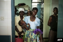 FILE - An HIV-positive mother holds her sick child at the Thyolo District hospital in Malawi, Nov. 26, 2014.