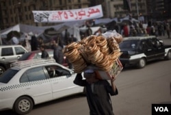 Seorang pria Mesir menggotong sebuah keranjang berisi roti untuk dijual di Tahrir Square, Minggu (2/13).
