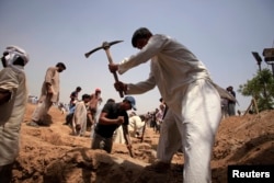 FILE - Members of the Ahmadi Muslim community dig graves for victims in Chenab Nagar, located in Punjab's Chiniot district, about 200 kilometers northwest of Lahore, May 29, 2010. At least 70 people were killed in an attack.