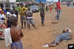 People stand around a man, right, suspected of suffering from the Ebola virus in a main street and busy part in Monrovia, Liberia, Sept. 12, 2014.