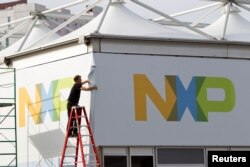 FILE - A man works on a tent for NXP Semiconductors in preparation for the 2015 International Consumer Electronics Show (CES) at Las Vegas Convention Center in Las Vegas, Nevada, Jan. 4, 2015.
