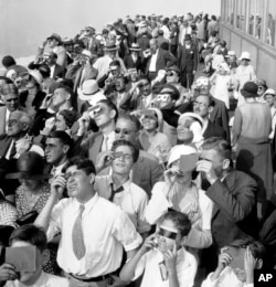 FILE - Eclipse watchers squint through protective film as they view a partial eclipse of the sun from the top deck of New York's Empire State Building in New York, Aug. 31, 1932.