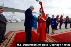 U.S. Secretary of State John Kerry accepts a gift of aaruul -- dried cheese curds -- from a woman in traditional Mongolian dress greets as he arrives at Chinggis Khaan International Airport in Ulaanbataar, Mongolia, June 5, 2016.