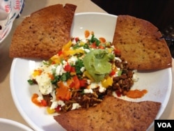 Sepiring sarapan berisikan sosis Chorizo, kacang hitam, nasi, keju kambing, telur orak-arik, guacamole, salsa roja, tortila. (Photo: Julia Taboh / VOA)
