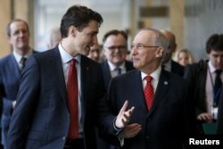 Canadian Prime Minster Justin Trudeau, left, arrives with Edmond Mulet, Assistant Secretary-General for Peacekeeping Operations at the United Nations before a news conference in the lobby of the United Nations in New York, March 16, 2016.